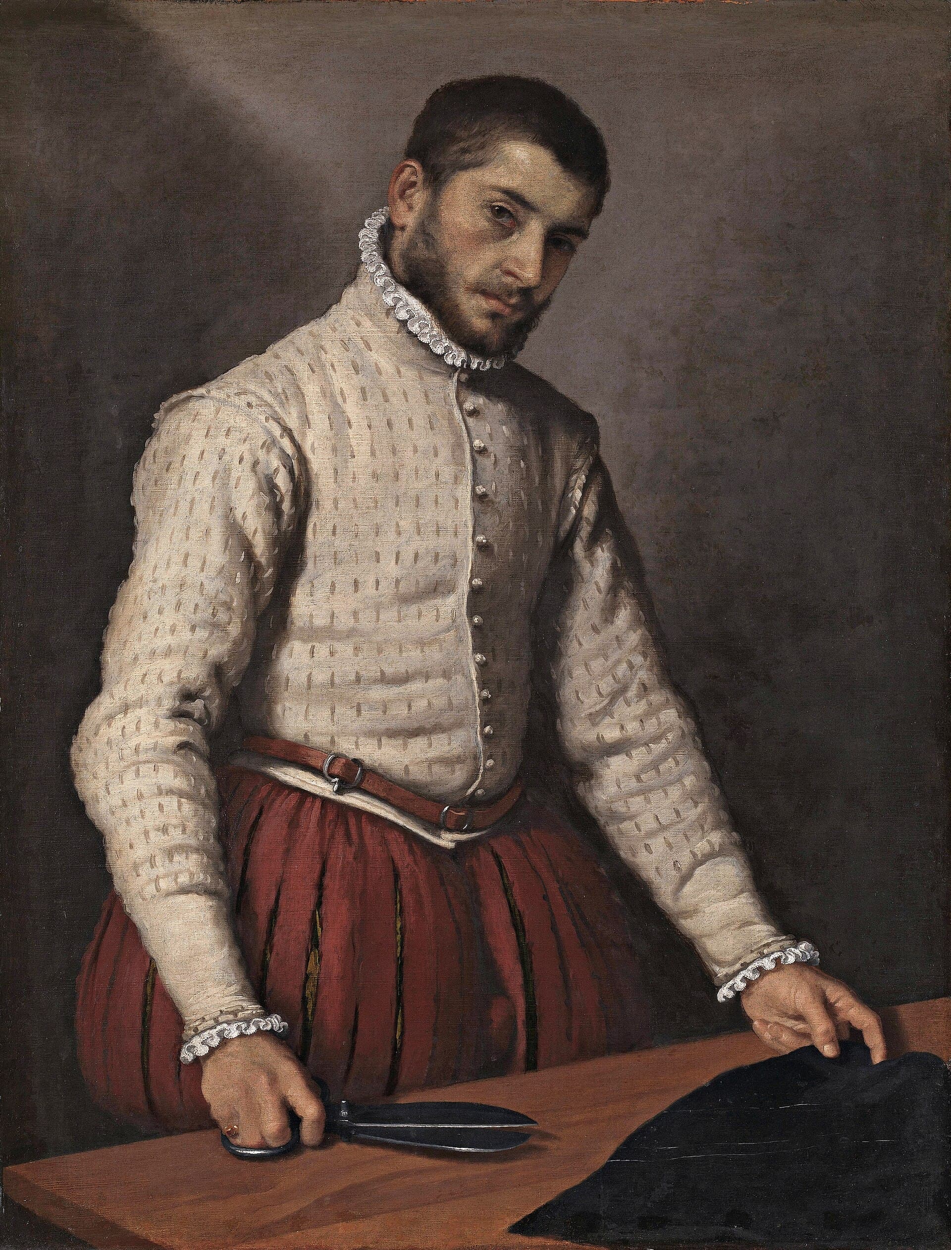 Giovanni Battista Moroni, Krawiec, ok. 1570, olej - mężczyzna w białym pikowanym kaftanie i czerwonych spodniach stoi przy drewnianym stole, w prawej dłoni trzyma rozwarte nożyce, lewą przytrzymuje czarne sukno, patrzy na widza