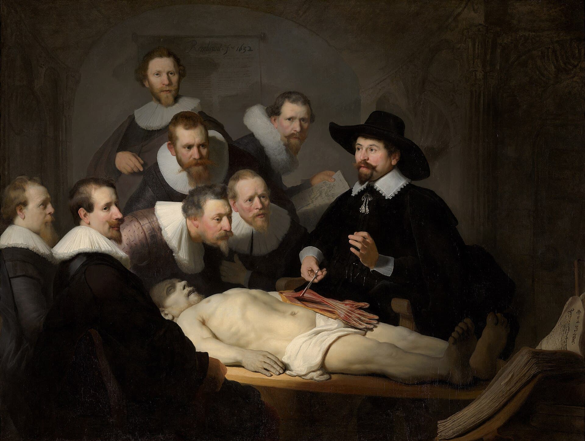 Rembrandt, Lekcja anatomii doktora Tulpa, 1632 — ciemne wnętrze, w którym całe światło pada na blade, nagie zwłoki leżące w poprzek drewnianego stołu, głową w lewo. Z prawej lekarz w szerokim czarnym kapeluszu i białej kryzie podważa pęsetą odsłonięte, czerwone mięśnie przedramienia, a przy stopach zmarłego leży otwarta gruba księga.