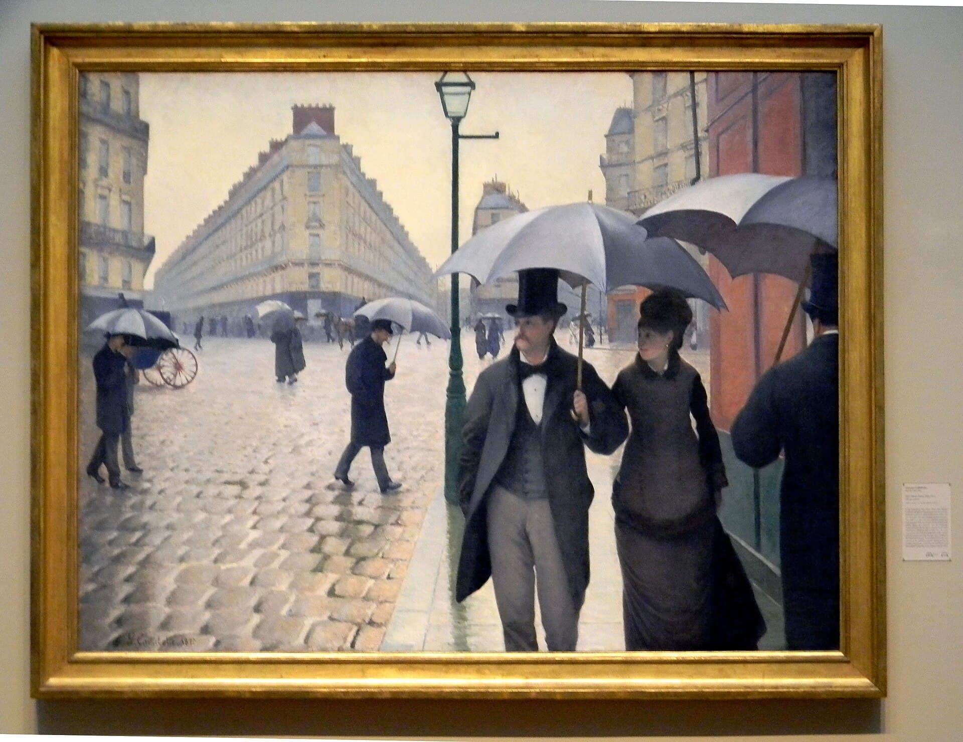 Gustave Caillebotte, Paryska ulica w deszczu (1877) — szeroki bruk, przechodnie z parasolami, na pierwszym planie para idąca razem wprost na widza