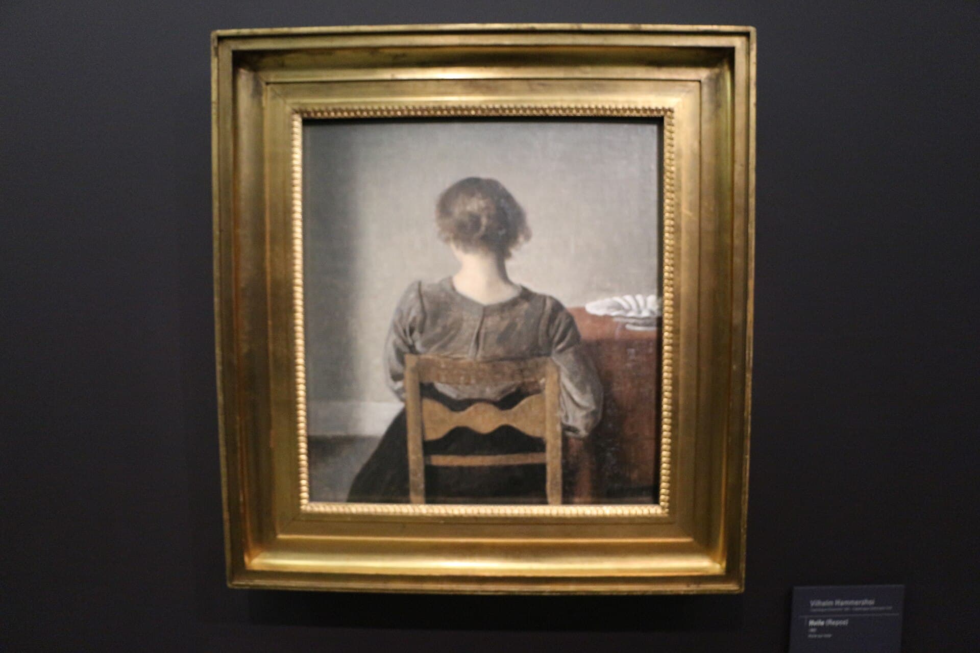 Vilhelm Hammershøi, Odpoczynek (Hvile, 1905) - kobieta siedząca tyłem, z odsłoniętym karkiem, twarz ukryta przed widzem