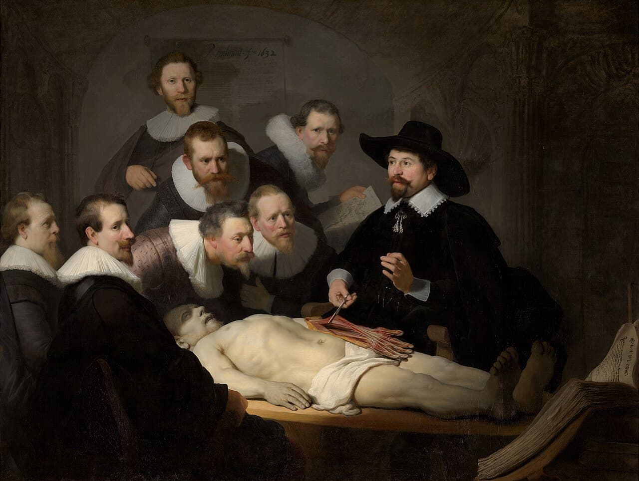 Rembrandt, Lekcja anatomii doktora Tulpa, 1632 — ciemne wnętrze, w którym całe światło pada na blade, nagie zwłoki leżące w poprzek drewnianego stołu, głową w lewo. Z prawej lekarz w szerokim czarnym kapeluszu i białej kryzie podważa pęsetą odsłonięte, czerwone mięśnie przedramienia, a przy stopach zmarłego leży otwarta gruba księga.