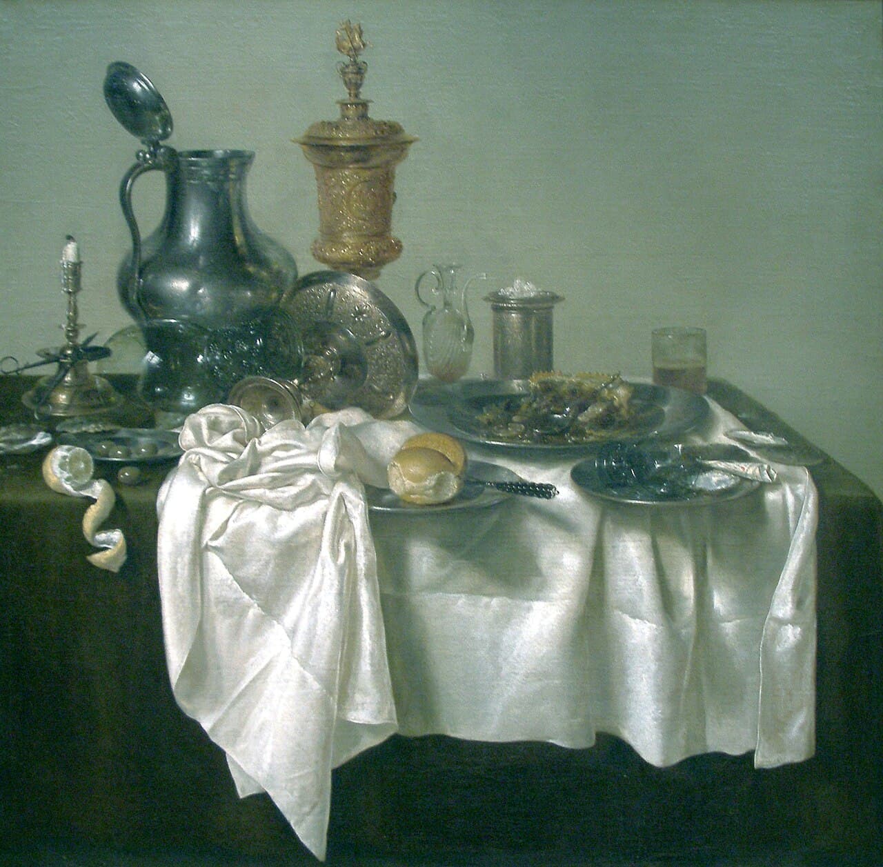 Willem Claesz. Heda, Śniadanie z pasztetem 1635 - martwa natura w chłodnej gamie szarości i srebra, na jasnym, pustym tle bez ściany i bez okna. Na ciemnym stole leży zsunięty w bok biały obrus, a na nim wysoki cynowy dzban z odchylonym wieczkiem, złocony puchar z pokrywą, świecznik ze zgaszoną świecą, nadkrojony pasztet na cynowym półmisku i kielich przewrócony na bok; z lewej krawędzi zwisa spiralnie zdjęta skórka cytryny.