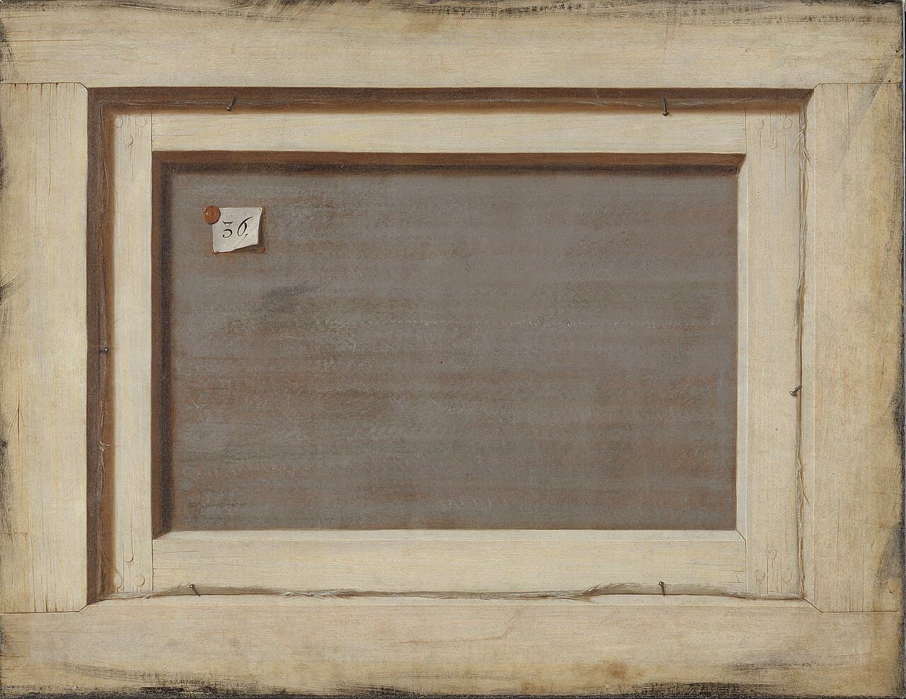 Cornelis Norbertus Gijsbrechts, Odwrocie oprawionego obrazu (ok. 1670) — całe płótno przedstawia tył innego obrazu: pośrodku szarobrunatna, niezamalowana tkanina, a wokół niej jasne, surowe listwy z widocznymi gwoździami i wystającymi nitkami płótna. W lewym górnym rogu tkaniny tkwi mała biała karteczka z odręczną liczbą 36, przytwierdzona czerwoną lakową pieczęcią.